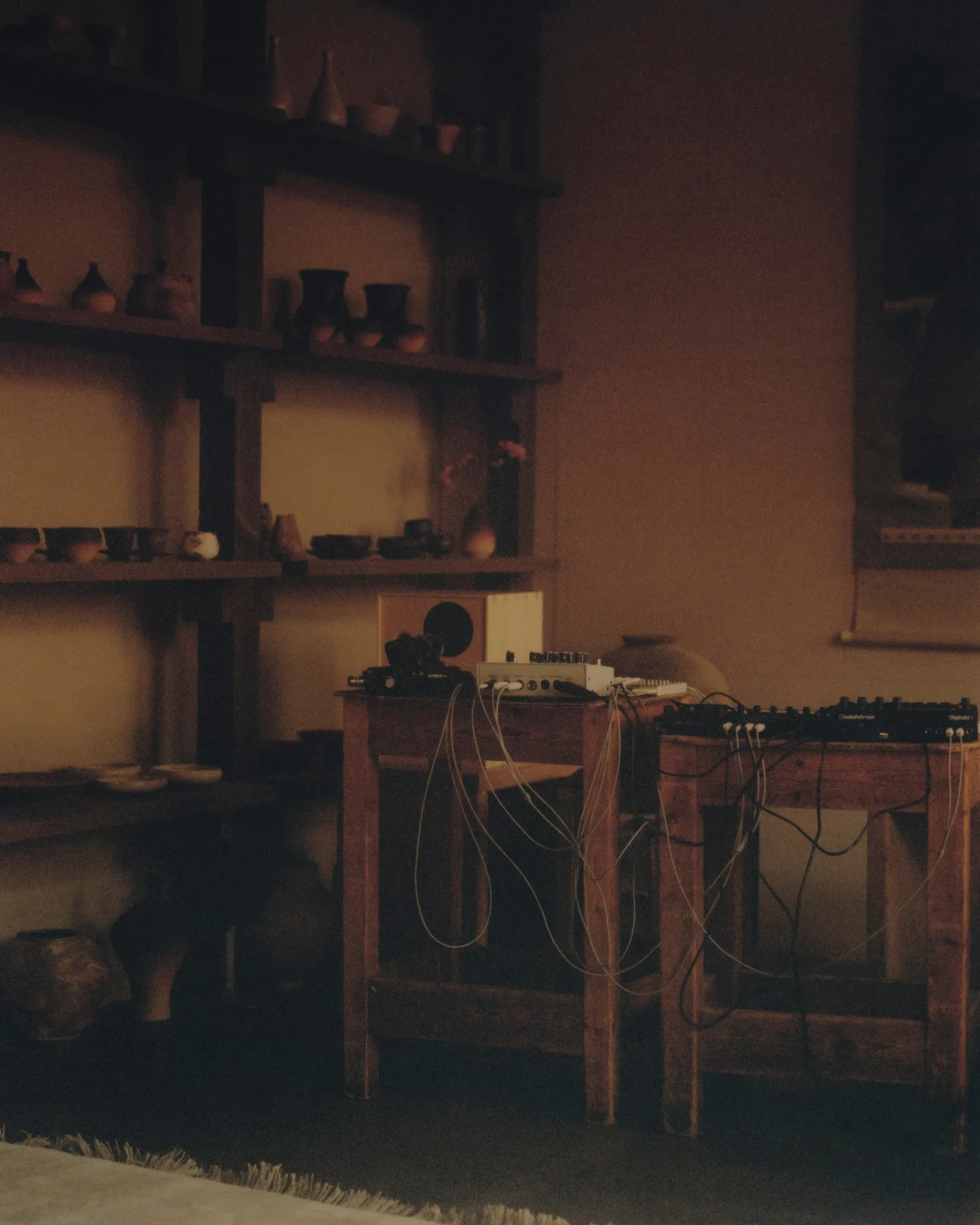 The Circle performance room – shelves of ceramics beside Huh Namhoon's cabled sound equipment in warm light