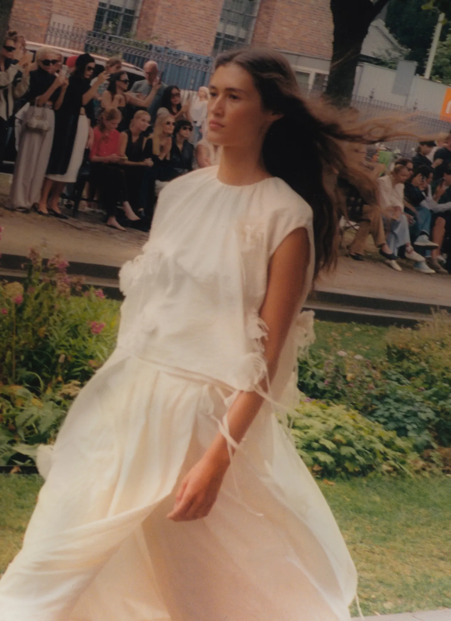 MKDT Studio SS27 – tiered white dress in motion on the outdoor runway
