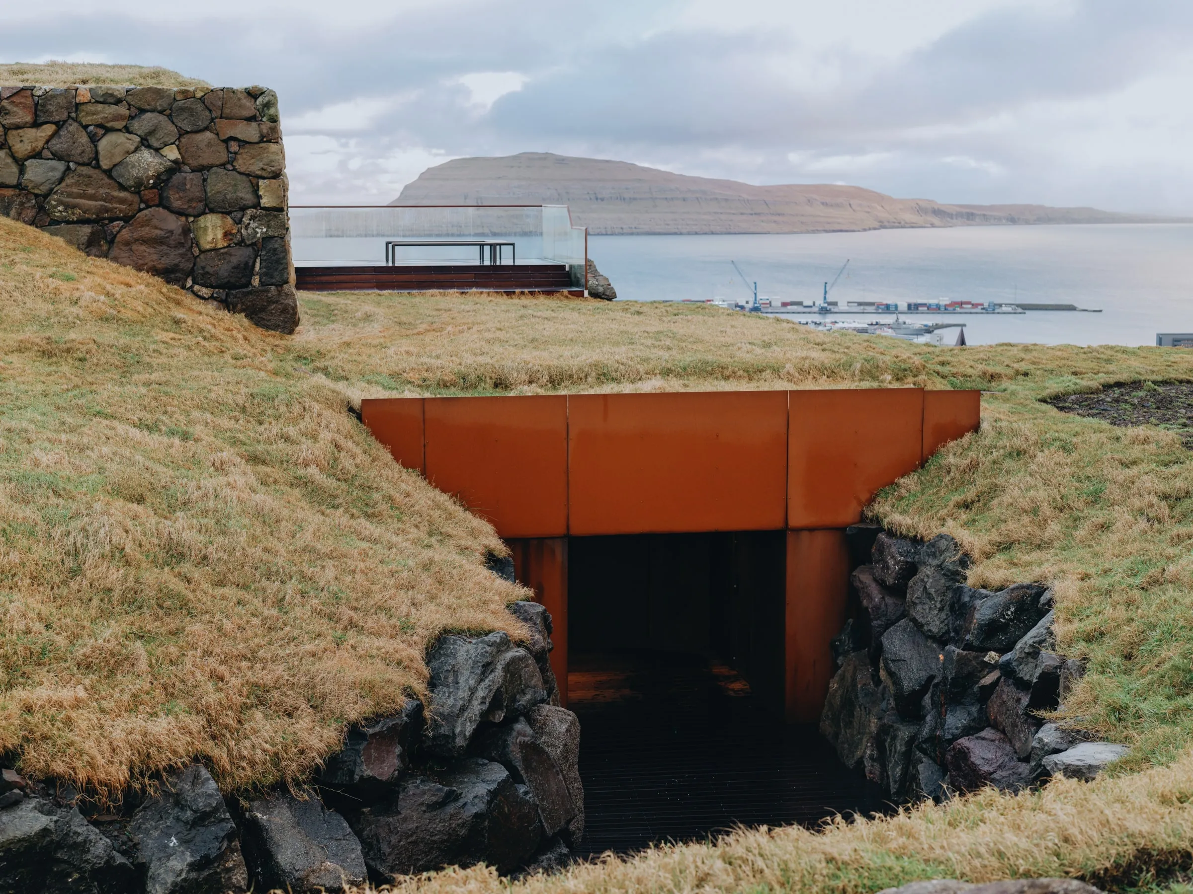 The entrance to Ress Spa, a corten doorway set into the turf of the hillside above Tórshavn, the harbour and Nólsoy beyond