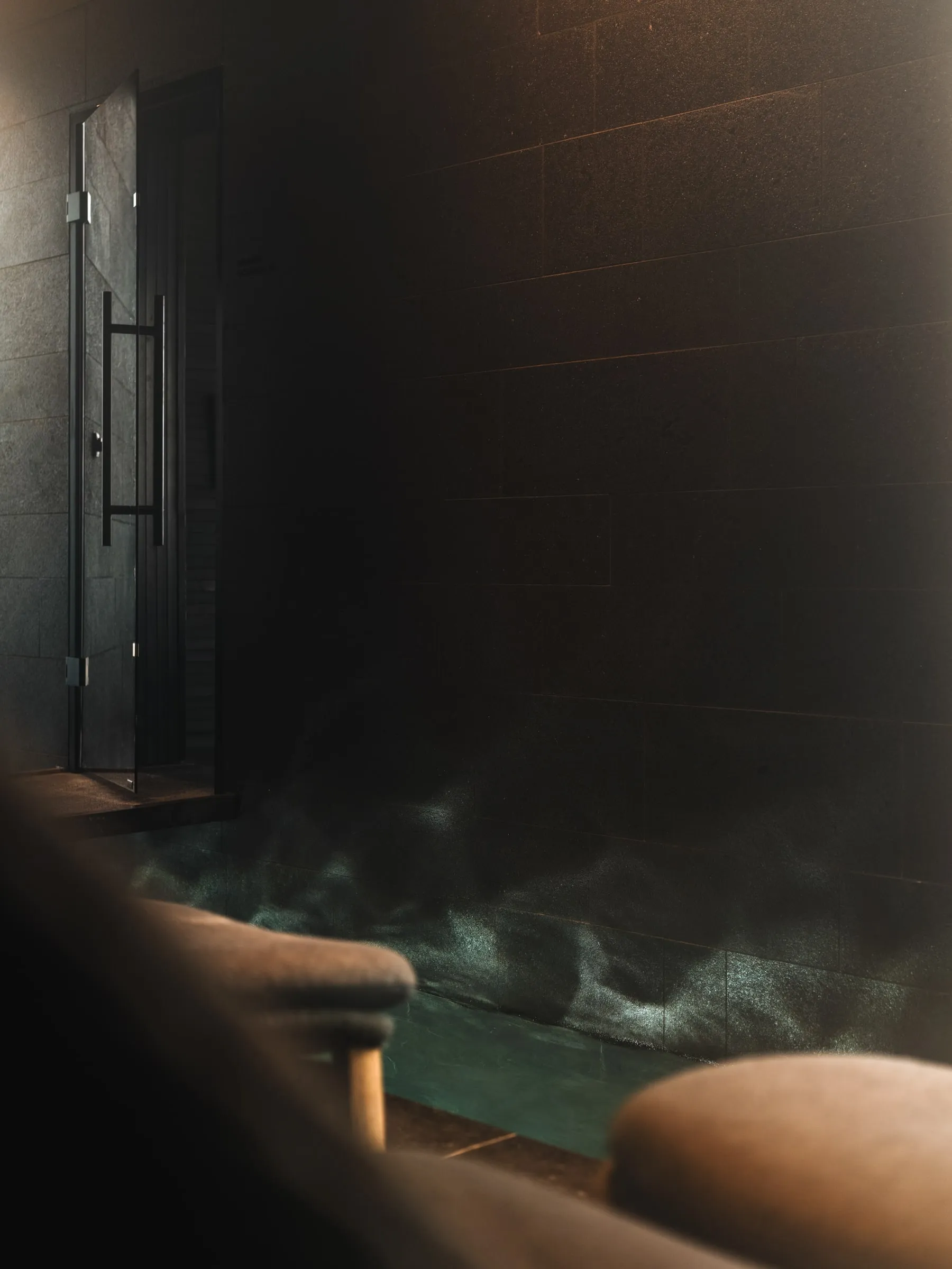 The dark timber sauna, and steam in the stone-clad steam bath